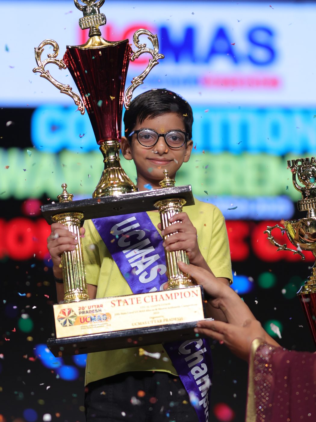 A UCMAS State Champion holding his trophy amid confetti