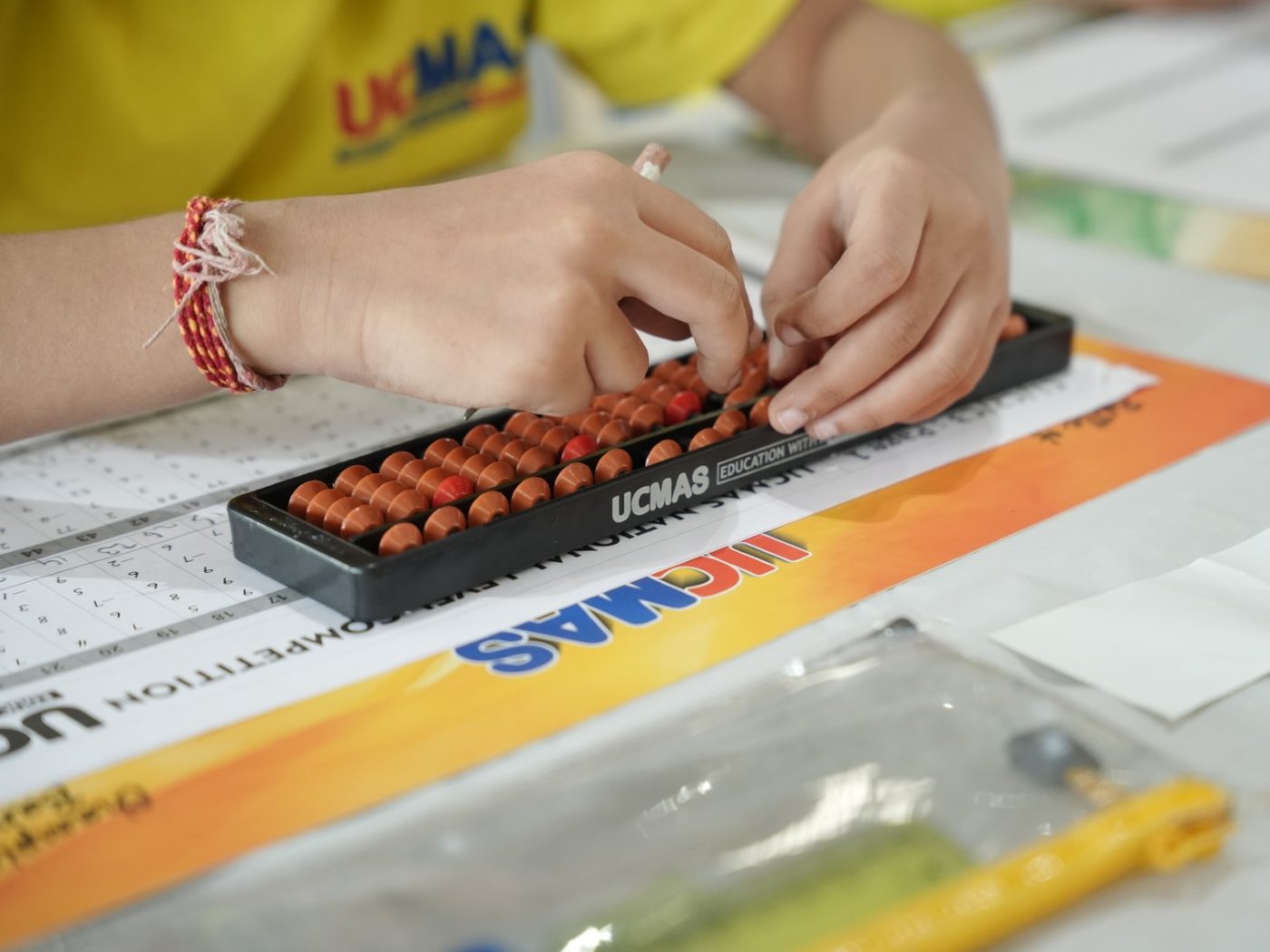 A student&rsquo;s hands on a UCMAS abacus during a competition